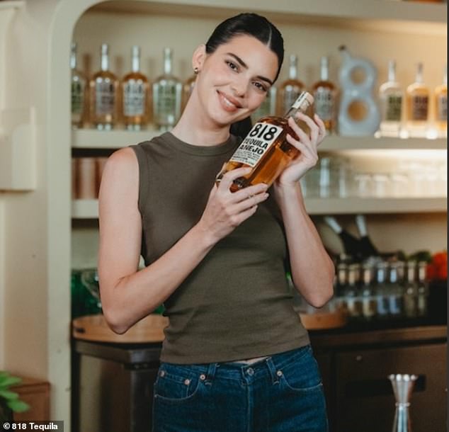 Kendall Jenner had fun behind a bar on National Tequila Day which fell on Wednesday. The reality TV star was bra-free as she wore an army green tank top that showed off her toned arms as she added skintight blue denim jeans